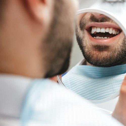 Patient smiling at reflection in handheld mirror