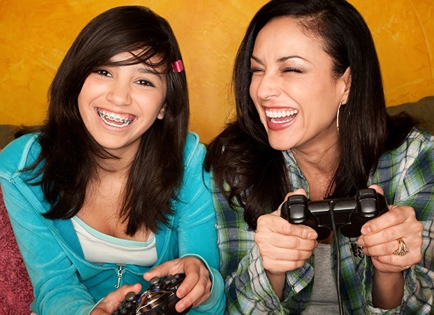 Teen with braces and her mother playing video games