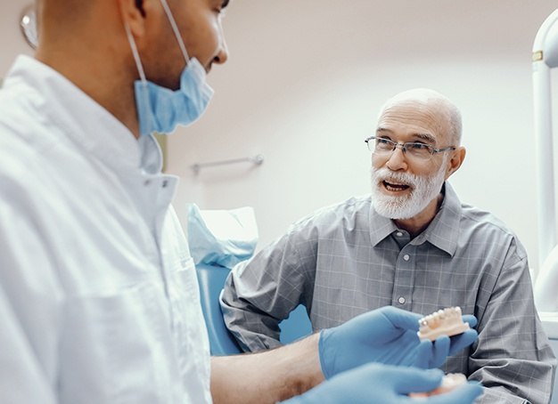 Dentist and patient looking at denture model