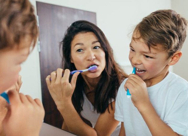 Mother and son preventing dental emergencies in Parsippany by brushing