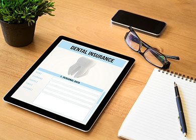 Tablet that reads Dental Insurance with nearby pen and pad
