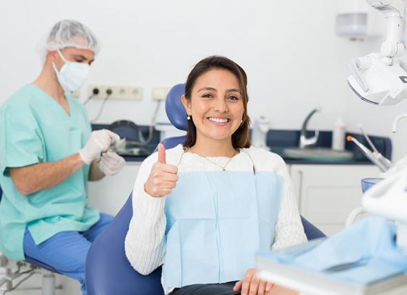 Happy female dental patient making thumbs up gesture