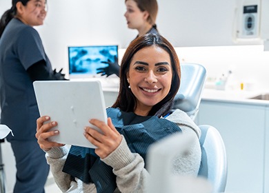 Patient smiling while holding mirror in treatment chair
