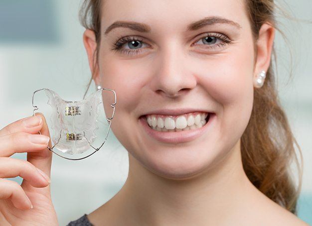Woman holding up her orthodontic oral appliance