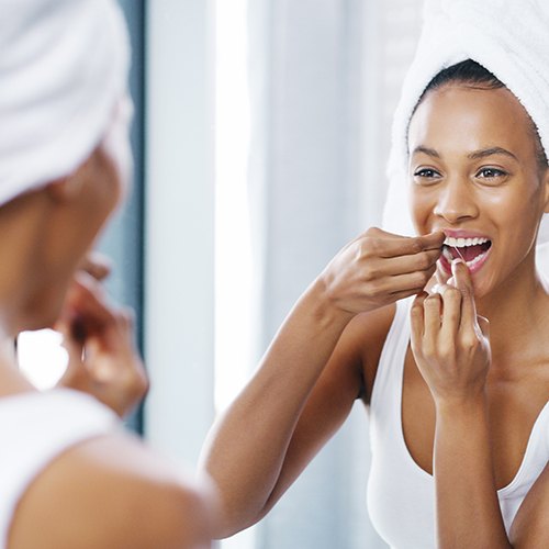 Closeup of woman flossing her teeth in bathroom