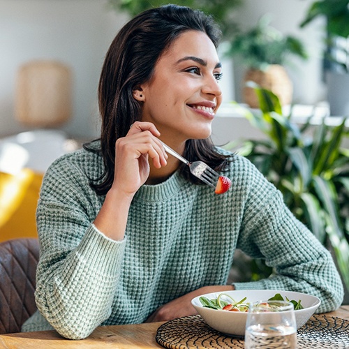 Woman smiling while eating healthy meal at home