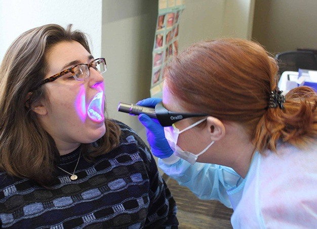 Dentist performing oral I D oral cancer screening