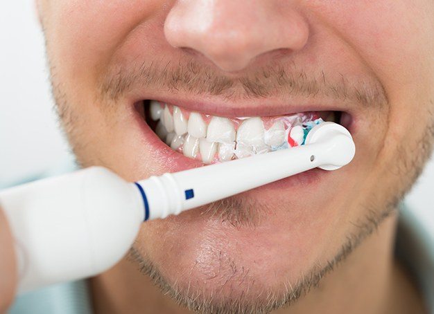 Closeup of patient using electric toothbrush