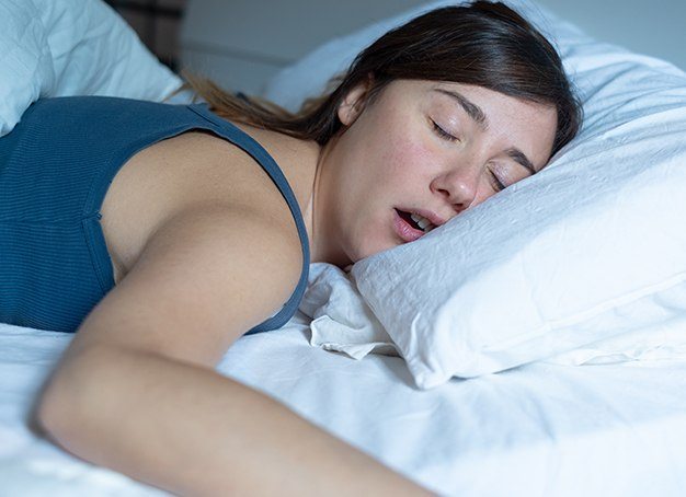 Woman in need of sleep apnea therapy snoring in bed