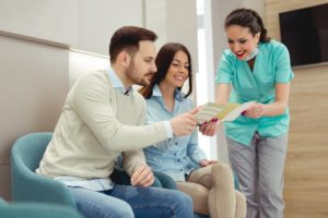 dental team member discussing dental insurance with two patients 