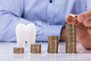 Coins and model tooth symbolizing how to maximize dental insurance benefits