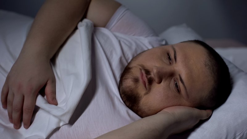 an overweight man lying awake at night because of insomnia caused by weight gain and sleep apnea in Parsippany