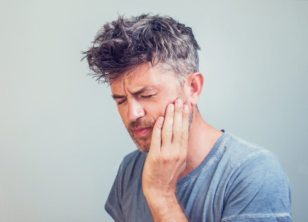 person holding cheek due to facial swelling