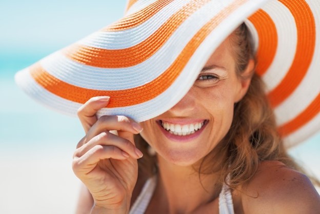 Smiling woman wearing beach hat.