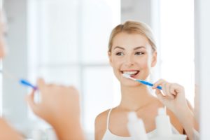 Young woman looking in mirror to brush her teeth