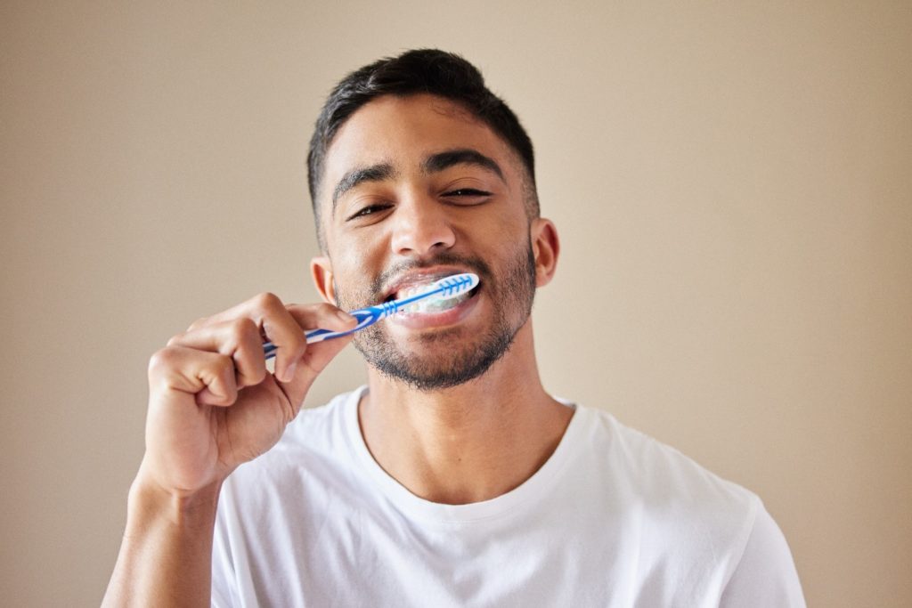 person brushing their teeth to practice good oral care habits