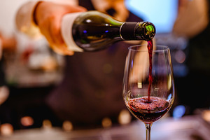 Close-up of pouring red wine into glass out of bottle