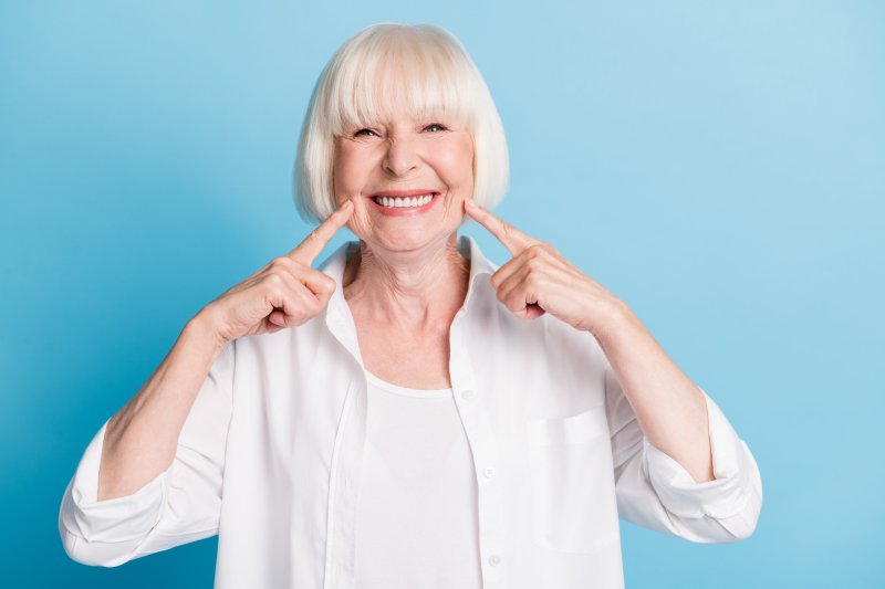 An older woman smiling with her dentures that she secured with denture adhesive