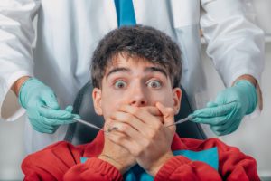 Anxious man in dental chair covering his mouth