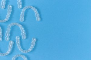 Several sets of clear aligners on a blue background