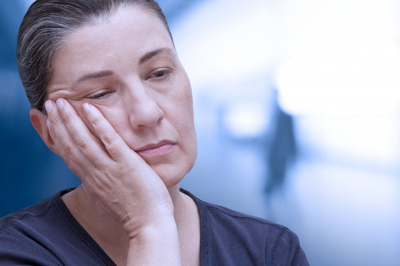 Woman holding her jaw due to TMJ disorder