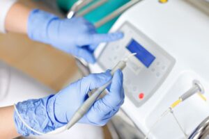 Gloved hands preparing soft tissue laser in dental office
