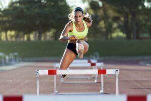 Athlete running and jumping hurdle.