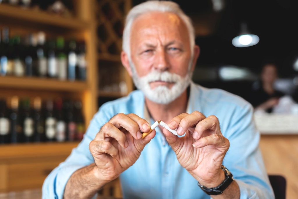 A man breaking a cigarette in half